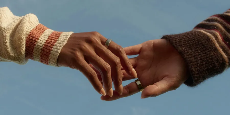 Zwei Hände mit Oura Ring vor blauem Himmel